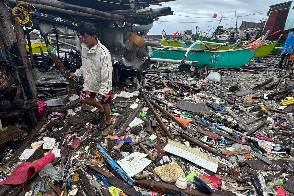 A man walks on debris washed ashore due to Typhoon Fung-wong along a coastal village on Monday, Nov. 10, 2025, in Navotas, Philippines. (AP Photo/Aaron Favila)