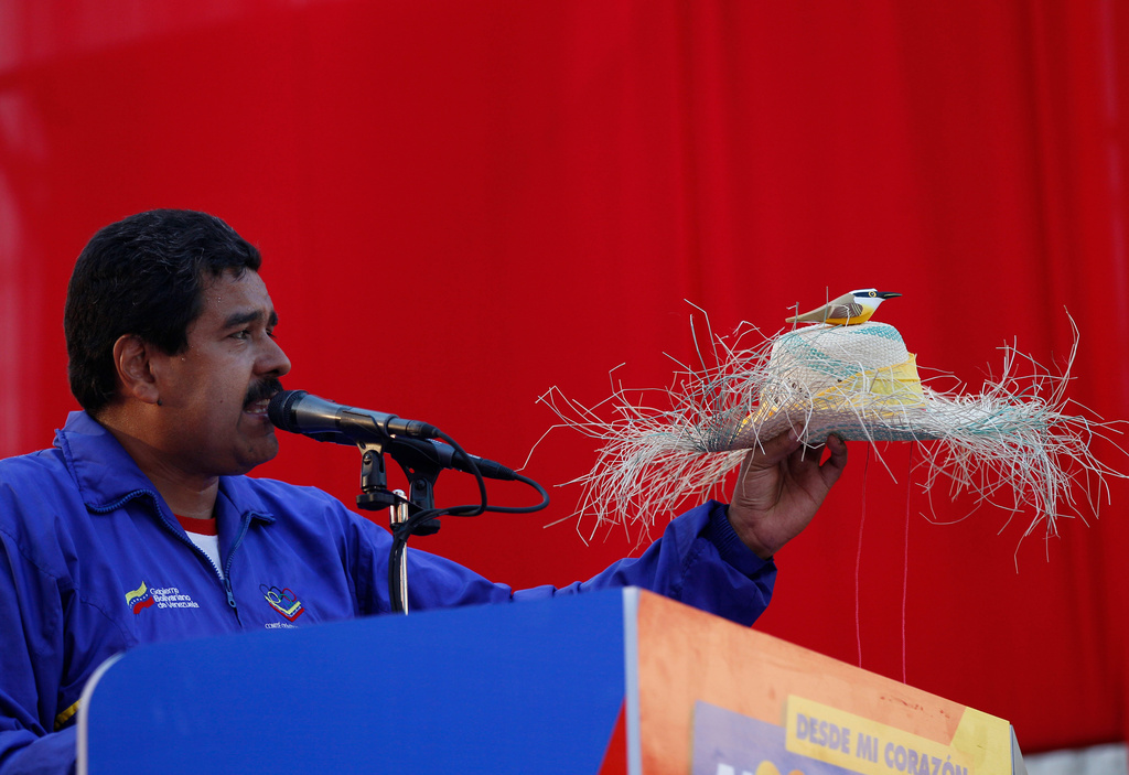 FILE - Venezuela's then acting President Nicolas Maduro holds a farm worker's hat with the figure of a bird perched on the hat's crown during a presidential election campaign rally in Catia La Mar, Venezuela, April 9, 2013. Maduro assured during a campaign rally that the late President Hugo Chavez appeared to him as a "very small bird" to give him his blessing. (AP Photo/Ariana Cubillos, File)