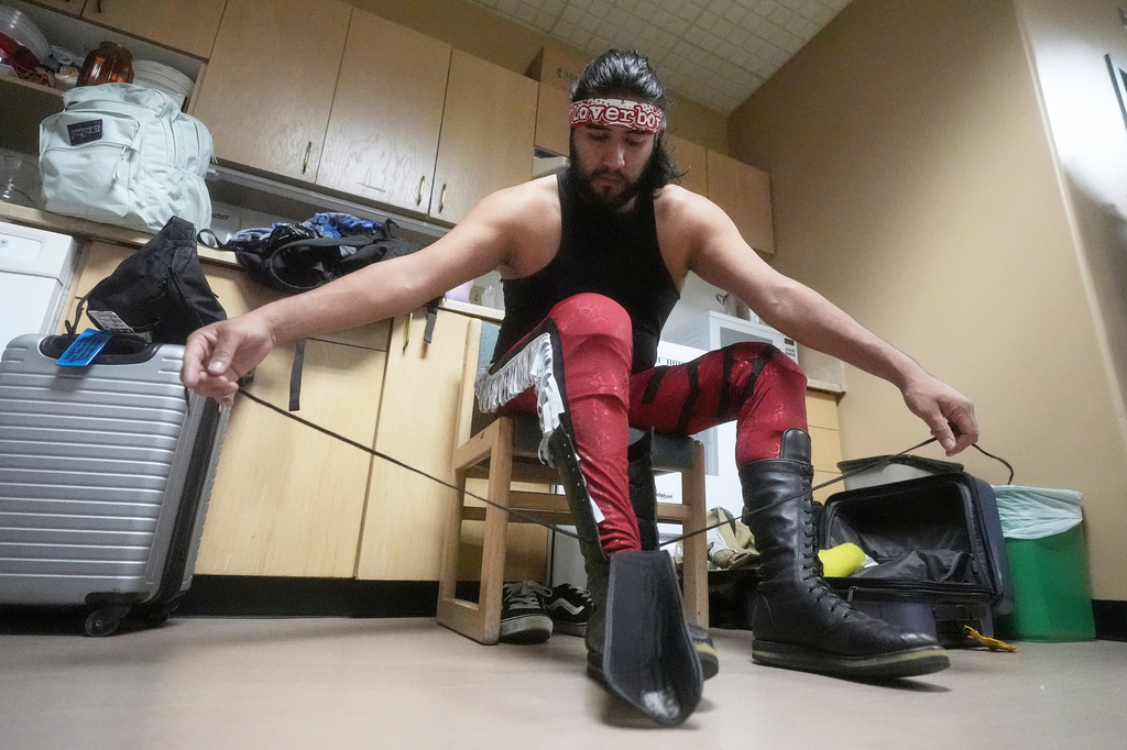Wrestler Loverboy Leo laces his boots before his match at a Lucha Libro pro wrestling event at Benicia Public Library Saturday, May 2, 2026, in Benicia, Calif. (AP Photo/Jeff Chiu)