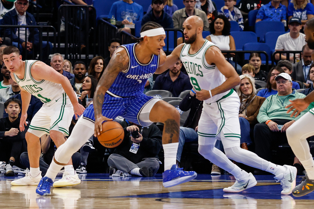 Orlando Magic forward Paolo Banchero, left,is defended by Boston Celtics guard Derrick White (9) during the first half of an NBA basketball game, Sunday, Nov. 9, 2025, in Orlando, Fla. (AP Photo/Kevin Kolczynski)
