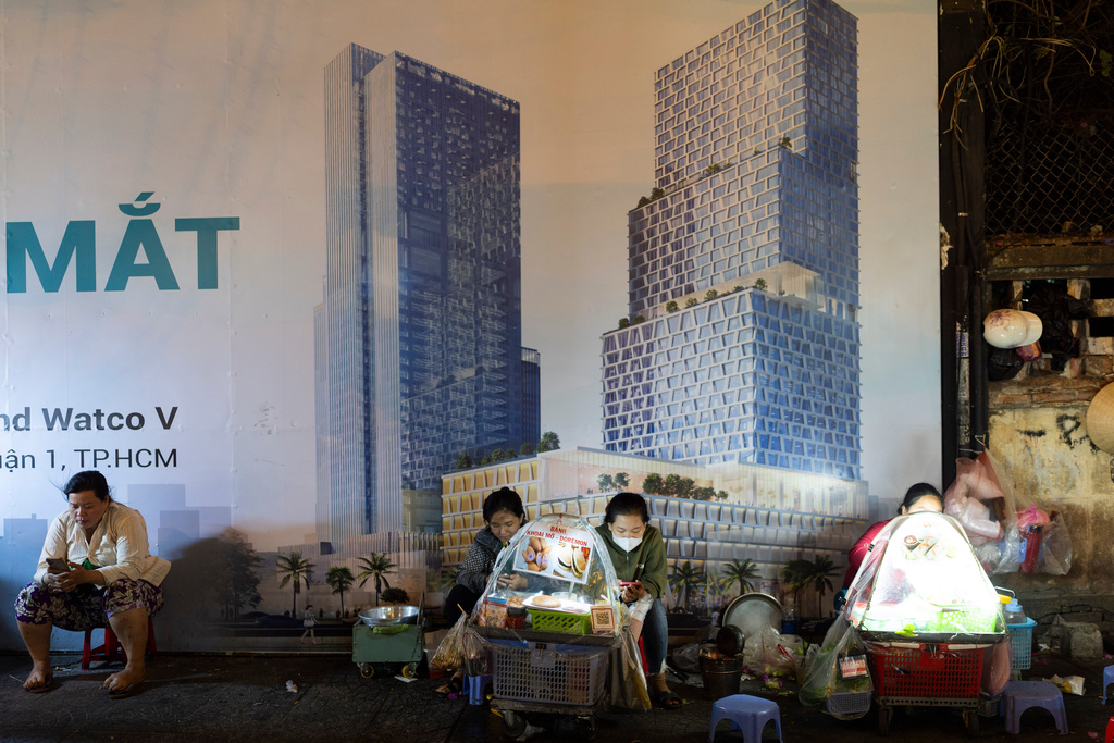 FILE- Food vendors sit on a sidewalk alongside the construction site of commercial buildings in Ho Chi Minh City, Vietnam, Jan. 11, 2024. (AP Photo/Jae C. Hong, File)