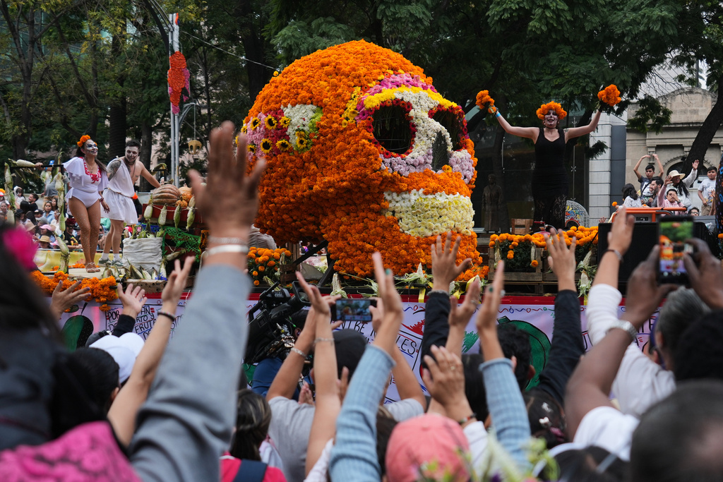 Spectators cheer as they watch the annual Day of the Dead parade in Mexico City, Saturday, Nov. 1, 2025. (AP Photo/Claudia Rosel)