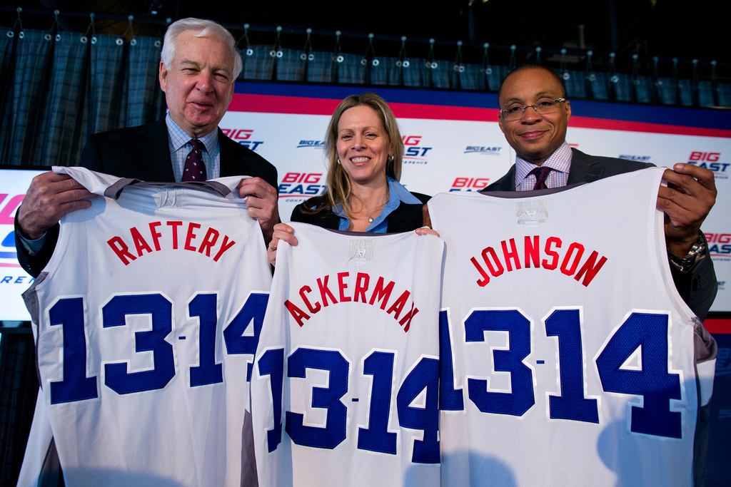 FILE - From left, basketball commentator Bill Raftery, Big East Commissioner Val Ackerman, and basketball commentator Gus Johnson hold jerseys at a news conference during the Big East Conference NCAA college basketball media day in New York, Oct. 16, 2013. (AP Photo/Craig Ruttle, File)