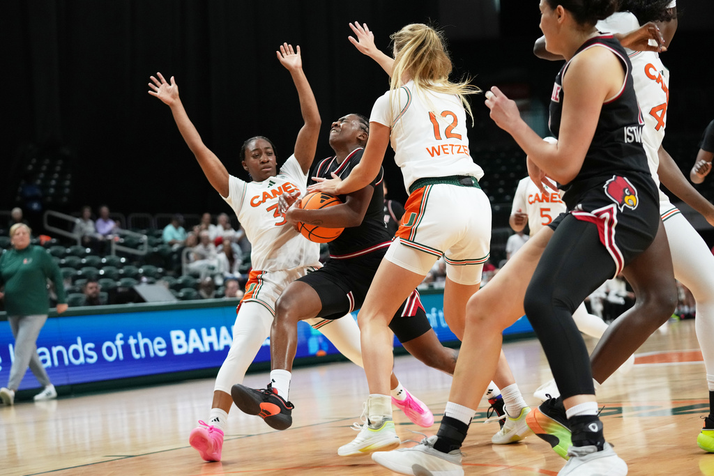 Louisville guard Reyna Scott, center, drives to the basket as Miami guard Amarachi Kimpson, left, and forward Natalie Wetzel (12) defend during the first half of an NCAA college basketball game, Thursday, Jan. 8, 2026, in Coral Gables, Fla. (AP Photo/Lynne Sladky)