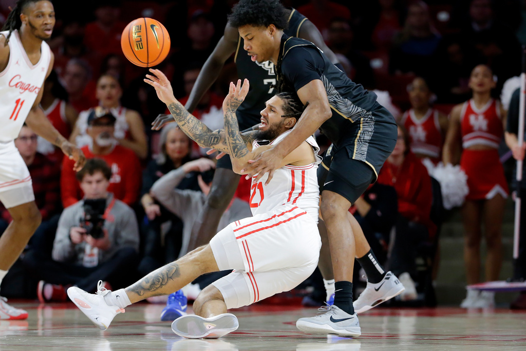 Houston guard Emanuel Sharp, left, passes the ball as he falls into Central Florida forward Jamichael Stillwell, right, during the first half of an NCAA college basketball game, Wednesday, Jan., 4, 2026, in Houston. (AP Photo/Michael Wyke)