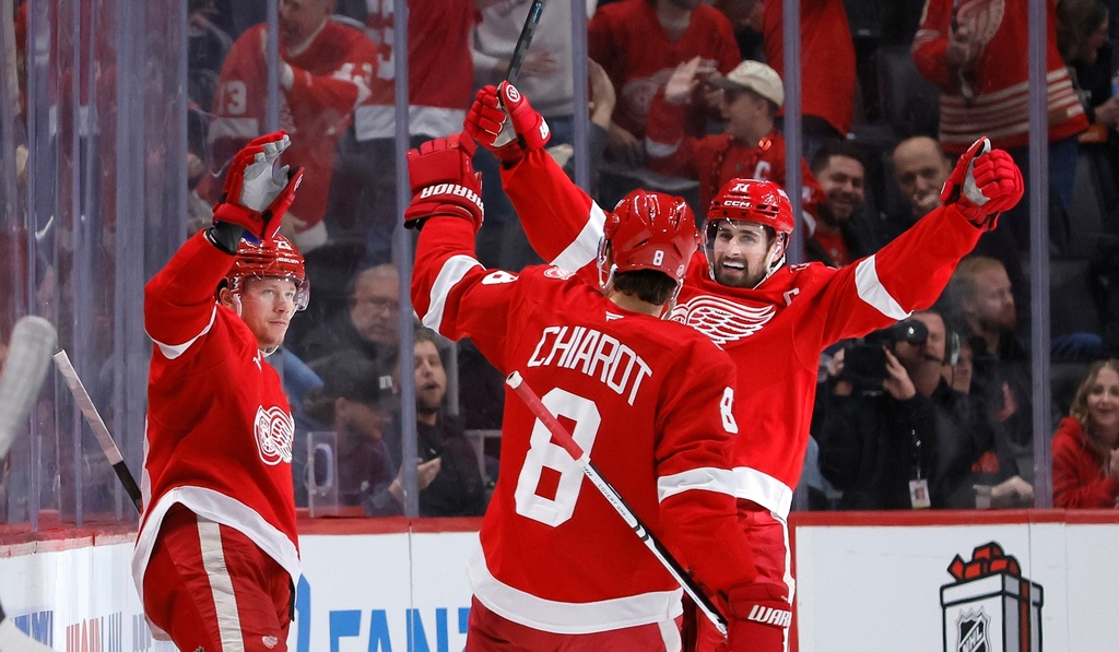 Detroit Red Wings left wing Lucas Raymond, left, celebrates with defenseman Ben Chiarot (8) and center Dylan Larkin, right, after scoring a goal against the Columbus Blue Jackets during the second period of an NHL hockey game Saturday, Nov. 22, 2025, in Detroit. (AP Photo/Duane Burleson)