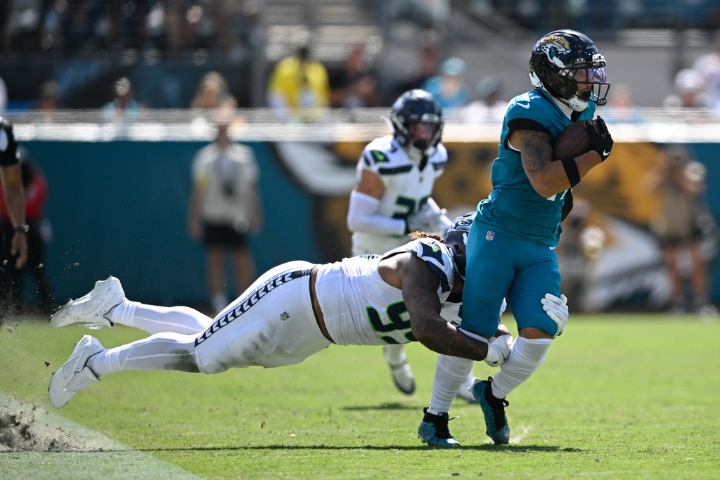 Jacksonville Jaguars wide receiver Parker Washington (11) is tackled by Seattle Seahawks defensive end Leonard Williams (99) during the first half of an NFL football game Sunday, Oct. 12 2025, in Jacksonville, Fla. (AP Photo/Phelan M. Ebenhack)