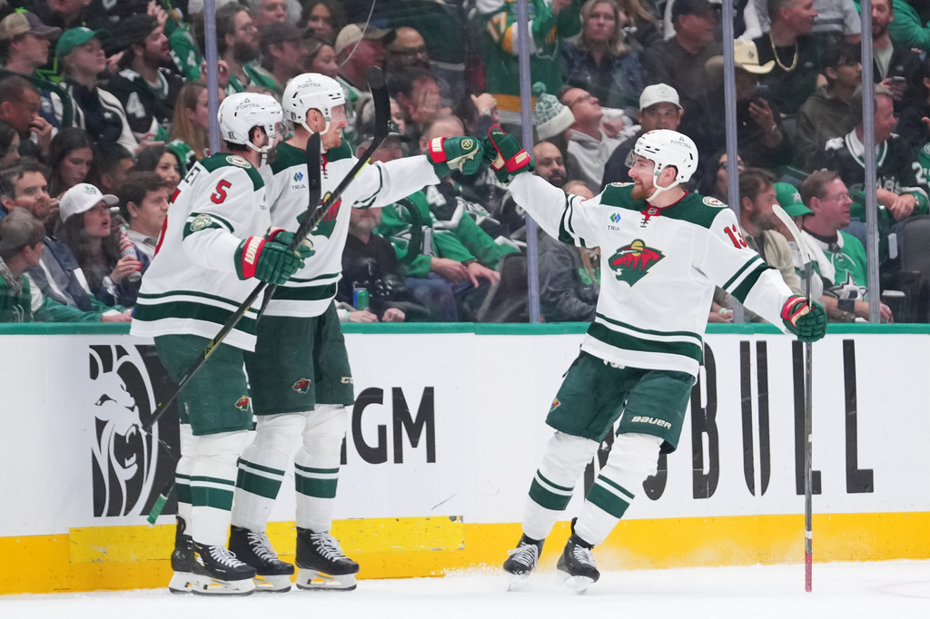 Minnesota Wild players, from left, Jake Middleton, Michael McCarron and Yakov Trenin react to a goal by McCarron during the third period in Game 5 of a first-round NHL Stanley Cup playoffs hockey series against the Dallas Stars, Tuesday, April 28, 2026, in Dallas. (AP Photo/Julio Cortez)
