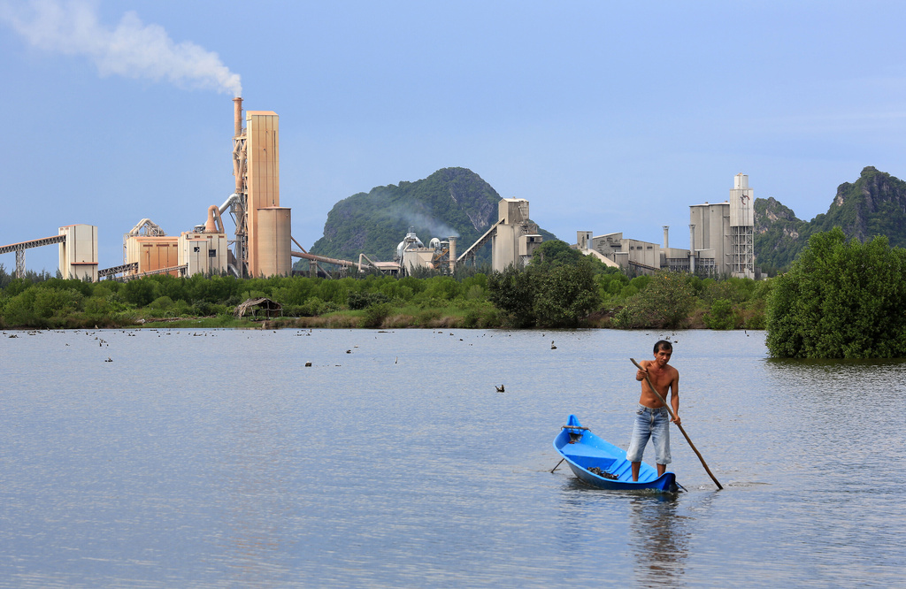 FILE- A man rows his boat on the fishing field outside the Holcim Vietnam cement company plant near the Moso mountains in Hong Chong, Vietnam, July 1, 2012. (AP Photo/Na Son Nguyen, File)