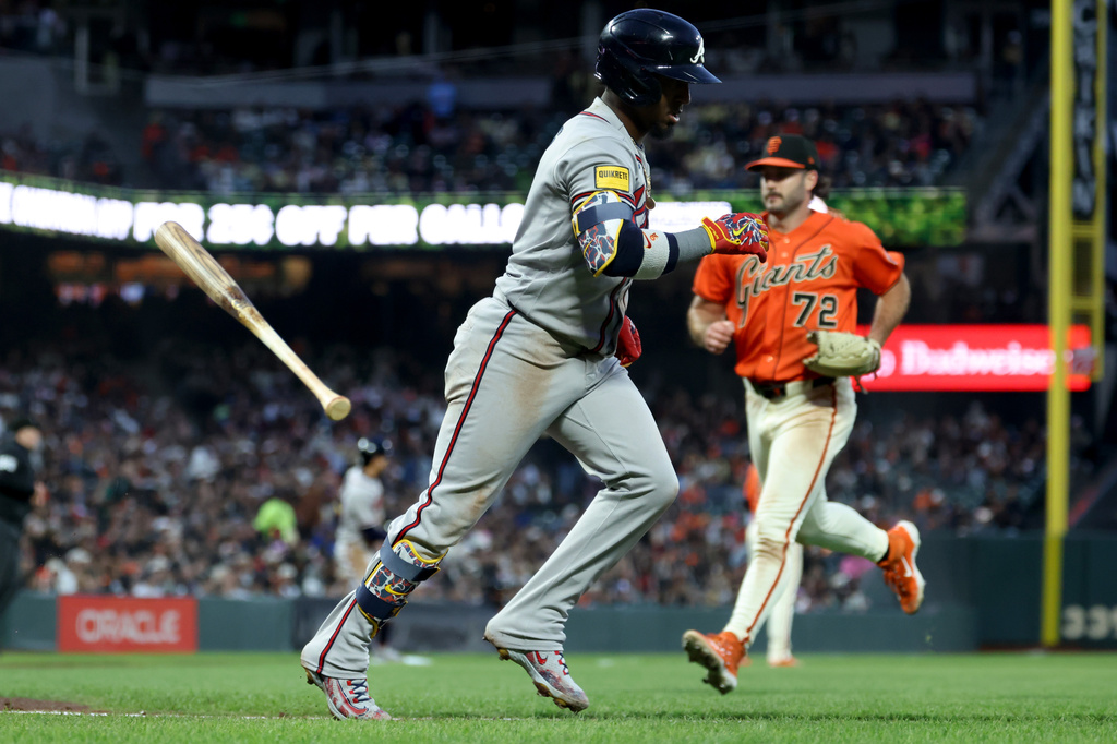 Atlanta Braves' Ozzie Albies, center, runs to first after hitting an RBI sacrifice fly in front of San Francisco Giants pitcher Trevor McDonald (72) during the fifth inning of a baseball game in San Francisco, Friday, June 26, 2026. (AP Photo/Jed Jacobsohn)