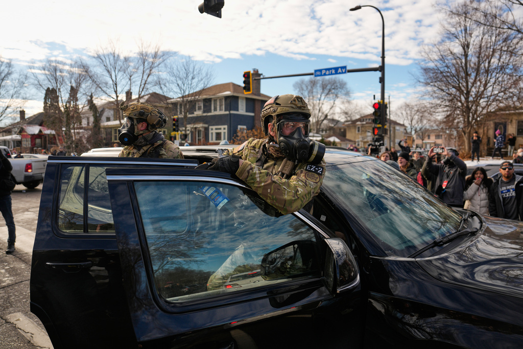 Federal immigration officers get in a car to leave a scene Monday, Jan. 12, 2026, in Minneapolis. (AP Photo/John Locher)