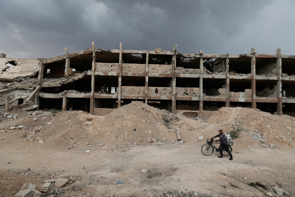 A man pushes his bicycle past the ruins of a school destroyed during the fighting between forces loyal to former President Bashar Assad and rebel groups, in the devastated Jobar neighborhood of Damascus, Syria, Thursday, Sept. 25, 2025. (AP Photo/Omar Sanadiki)