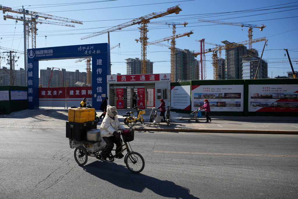 A food vendor passes a construction site in Beijing, China, Sunday, Feb. 8, 2026. (AP Photo/Ng Han Guan)