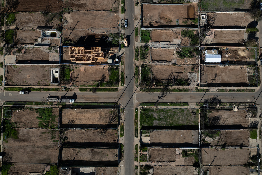 Cleared lots sit next to homes being rebuilt in the Pacific Palisades neighborhood of Los Angeles, Friday, Dec. 5, 2025, months after the Palisades Fire. (AP Photo/Jae C. Hong)