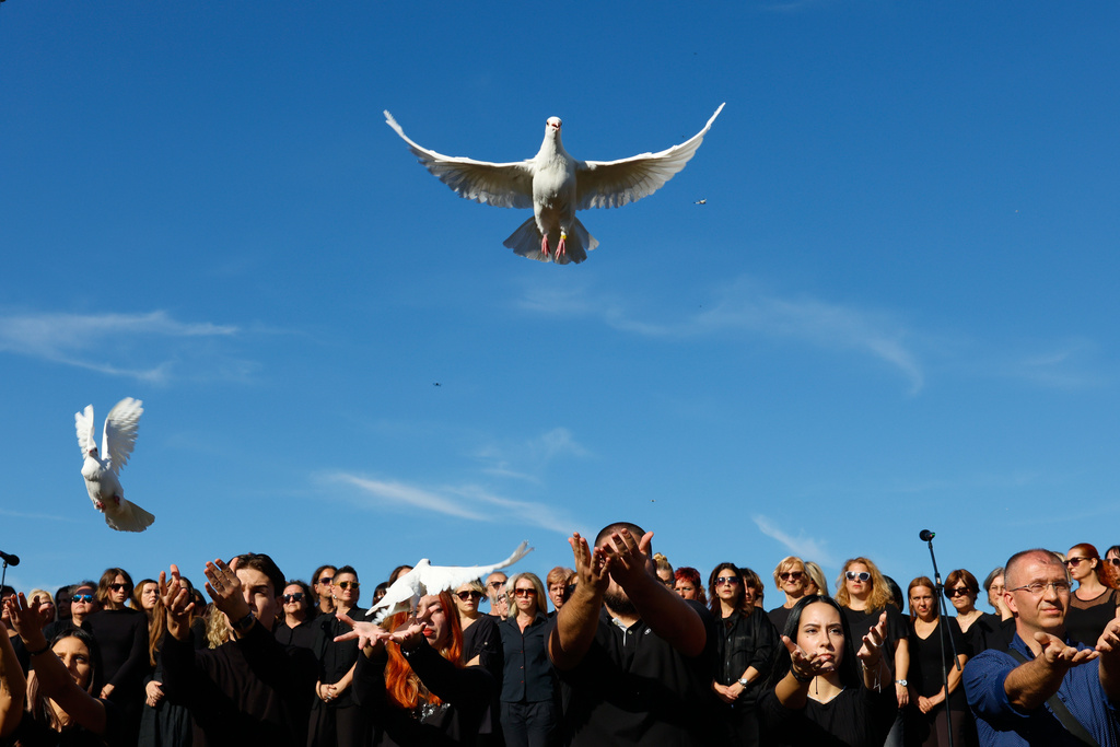 People release white doves in memory of the victims, outside the train station, on the first anniversary of the disaster that killed 16 people, in Novi Sad, Serbia, Saturday, Nov. 1, 2025. (AP Photo/Marko Drobnjakovic)