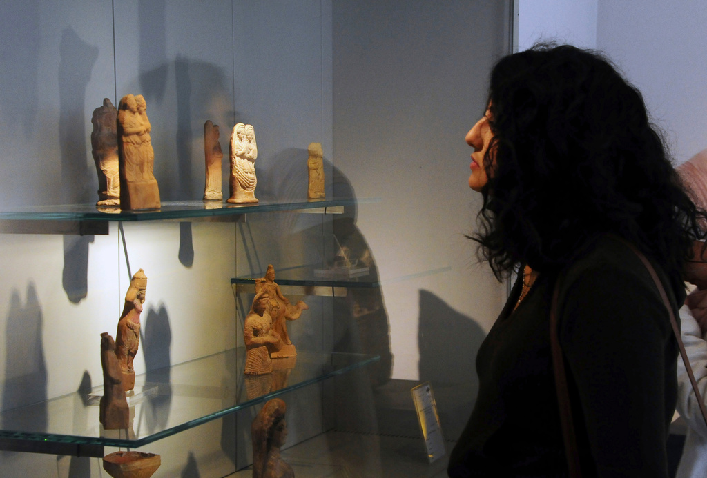 FILE - In this photo released by the Syrian official news agency SANA, a visitor looks at ancient artifacts during the reopening ceremony for Syria's National Museum, in Damascus, Syria, Oct. 28, 2018. (SANA via AP, File)