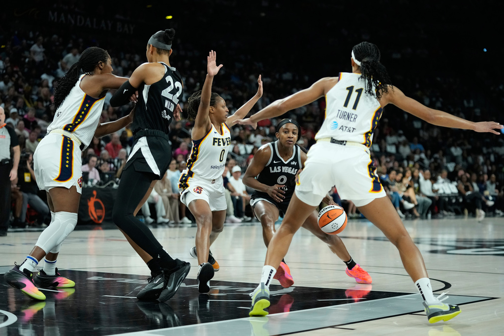 Las Vegas Aces guard Jackie Young (0) drives against Indiana Fever guard Kelsey Mitchell (0) during the first half of Game 2 of a WNBA basketball playoff semifinals series Tuesday, Sept. 23, 2025, in Las Vegas. (AP Photo/John Locher)