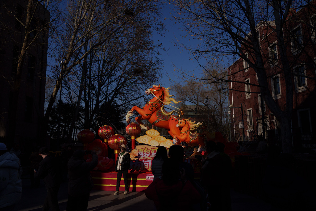 Visitors walk past illuminated festive decorations during the second day of Lunar New Year celebrations at a temple fair in Beijing on Wednesday, Feb. 18, 2026. (AP Photo/Vincent Thian)