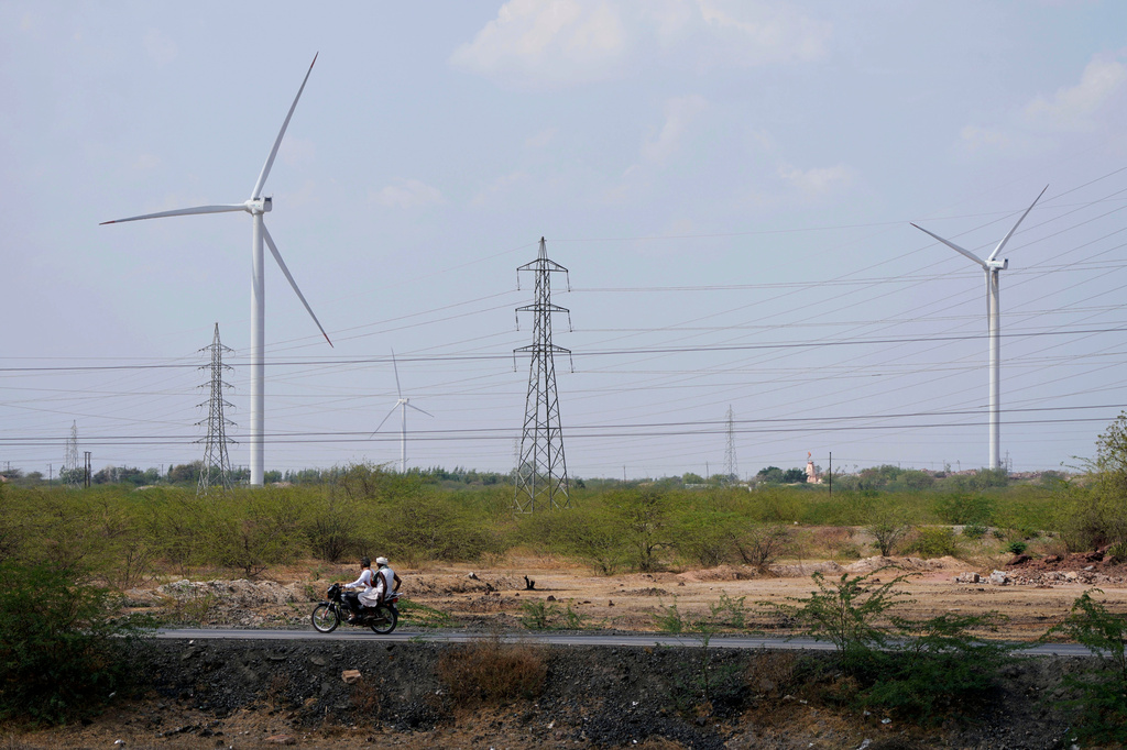FILE - A motorcyclist ride past wind turbines, an Adani Group project, near Sadla village in Surendranagar district of Gujarat state, India, March 20, 2023. (AP Photo/Ajit Solanki, File)