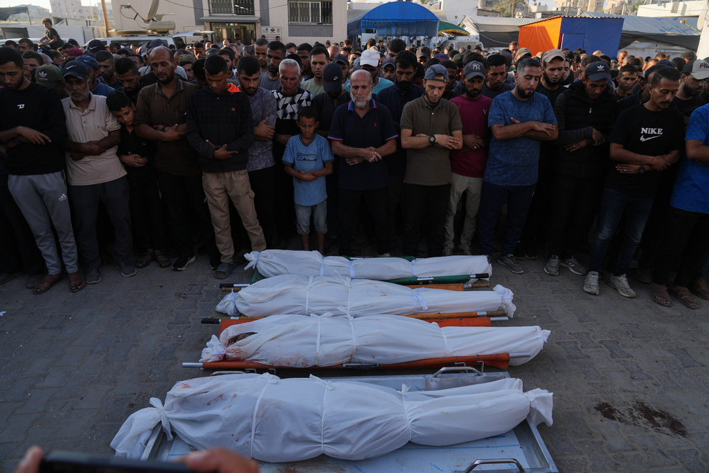Mourners pray over the bodies of Palestinians killed by Israeli fire, during their funeral at Al-Aqsa Hospital in Deir al-Balah, Gaza Strip, Sunday, Oct. 19, 2025. (AP Photo/Abdel Kareem Hana)