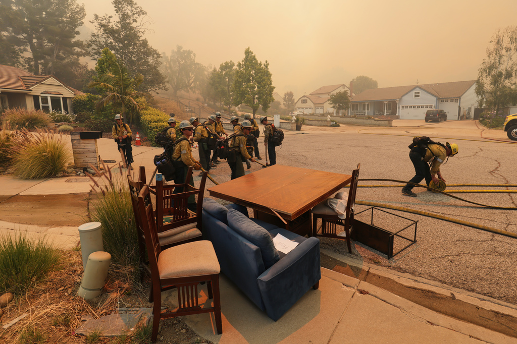 Fire crews roll out hoses at a cul-de-sac while battling the Sandy Fire Monday, May 18, 2026, in Simi Valley, Calif. (AP Photo/Ethan Swope)