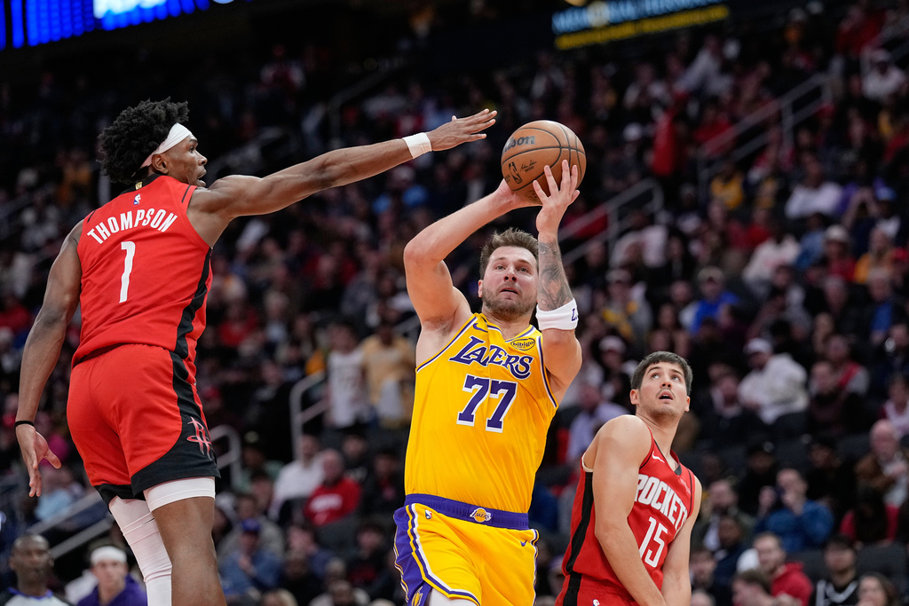Los Angeles Lakers' Luka Doncic (77) shoots as Houston Rockets' Amen Thompson (1) defends during the first half of an NBA basketball game Monday, March 16, 2026, in Houston. (AP Photo/David J. Phillip)