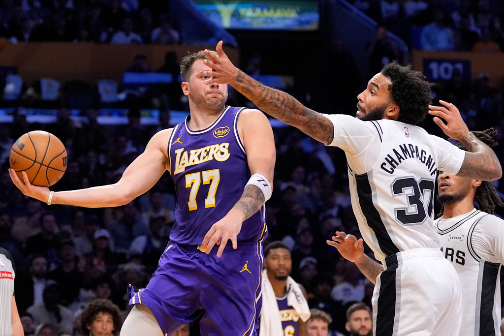 Los Angeles Lakers guard Luka Doncic, left, tries to pass as San Antonio Spurs forward Julian Champagnie defends during the first half of an NBA basketball game Wednesday, Nov. 5, 2025, in Los Angeles. (AP Photo/Mark J. Terrill)