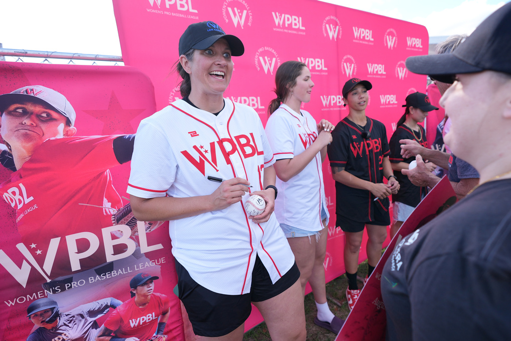 Meggie Meidlinger, left, talks with a fan as she signs a ball at a Women's Pro Baseball League fan fest event ahead of a spring training game between the Boston Red Sox and the Minnesota Twins, Thursday, March 19, 2026, in Fort Myers, Fla. (AP Photo/Rebecca Blackwell)