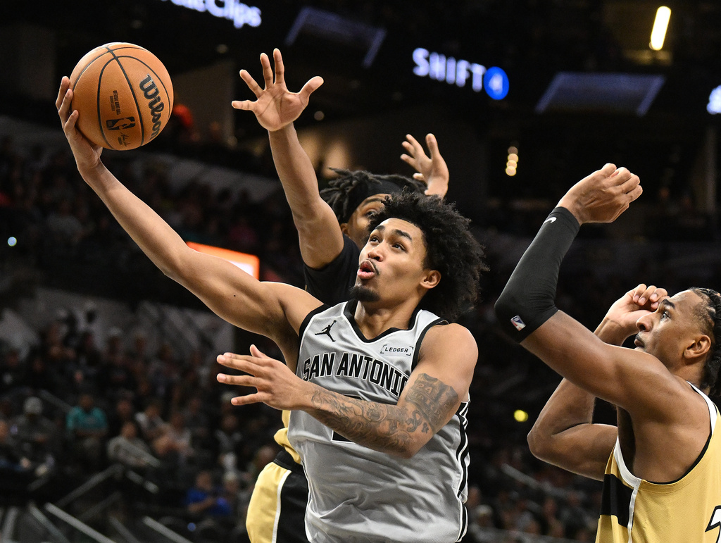 San Antonio Spurs guard Dylan Harper, front, drives for a layup as Washington Wizards guard Bilal Coulibaly, back, and center Alex Sarr, right, defend during the second half of an NBA basketball game in San Antonio, Thursday, Dec. 18, 2025. (AP Photo/Billy Calzada)