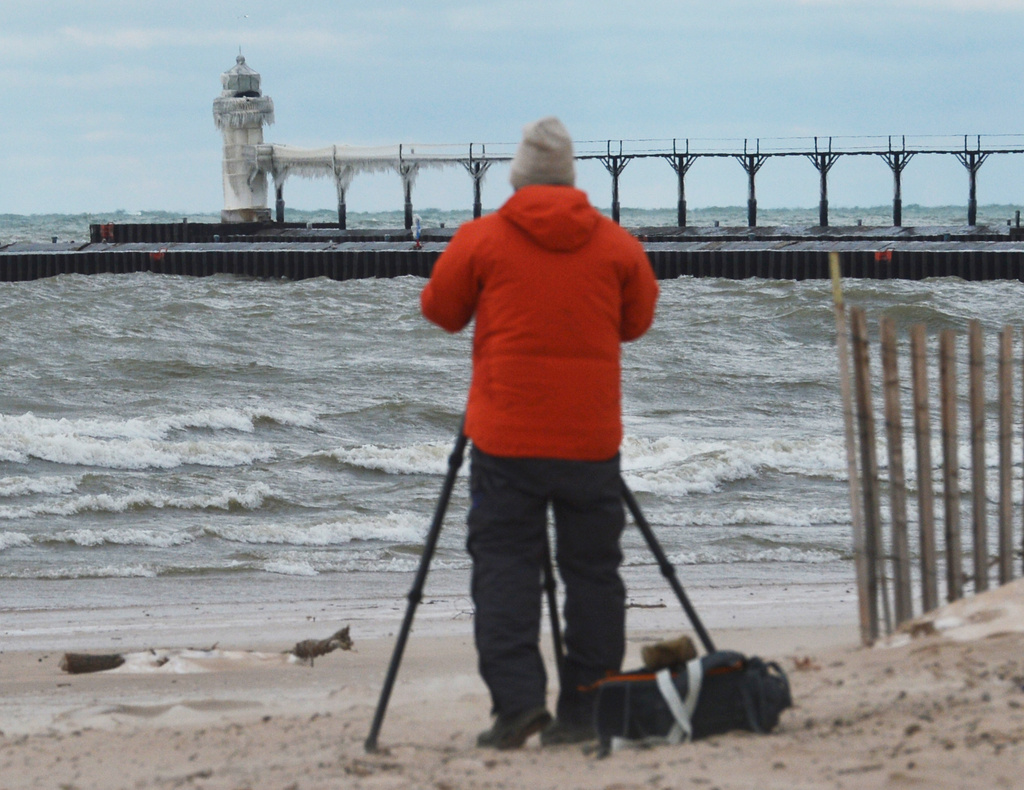 A photographer frames an image of an ice-covered Outer Lighthouse along Lake Michigan at Silver Beach in St. Joseph, Mich., on Tuesday, Dec. 30, 2025. (Don Campbell/The Herald-Palladium via AP)