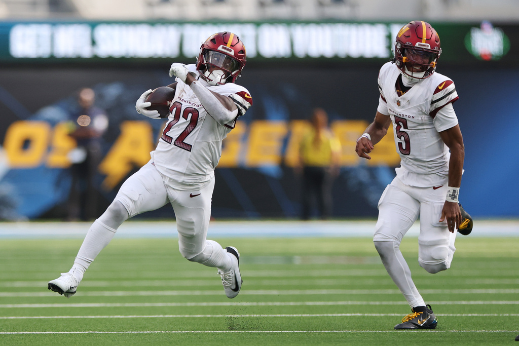 Washington Commanders running back Jacory Croskey-Merritt (22) runs in front of quarterback Jayden Daniels (5) during the second half of an NFL football game against the Los Angeles Chargers, Sunday, Oct. 5, 2025, in Inglewood, Calif. (AP Photo/Eric Thayer)