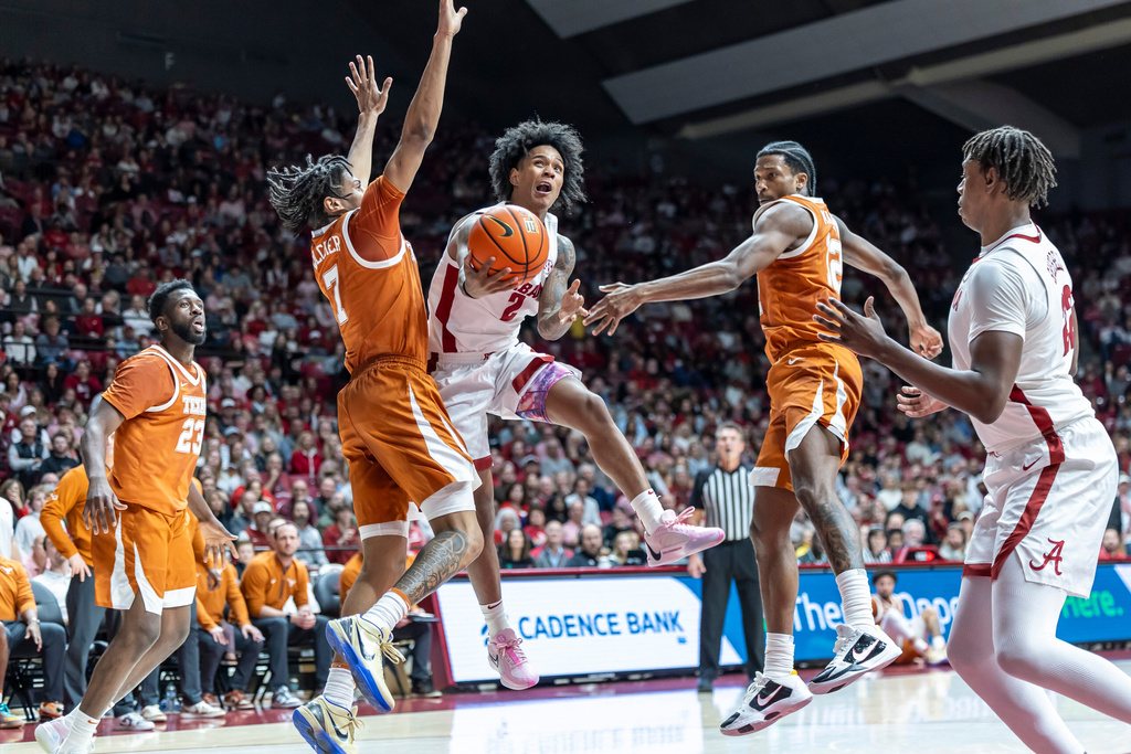 Alabama guard Aden Holloway (2) shoots between Texas guards Simeon Wilcher (7) and Tramon Mark (12) during the first half of an NCAA college basketball game, Saturday, Jan. 10, 2026, in Tuscaloosa, Ala. (AP Photo/Vasha Hunt)