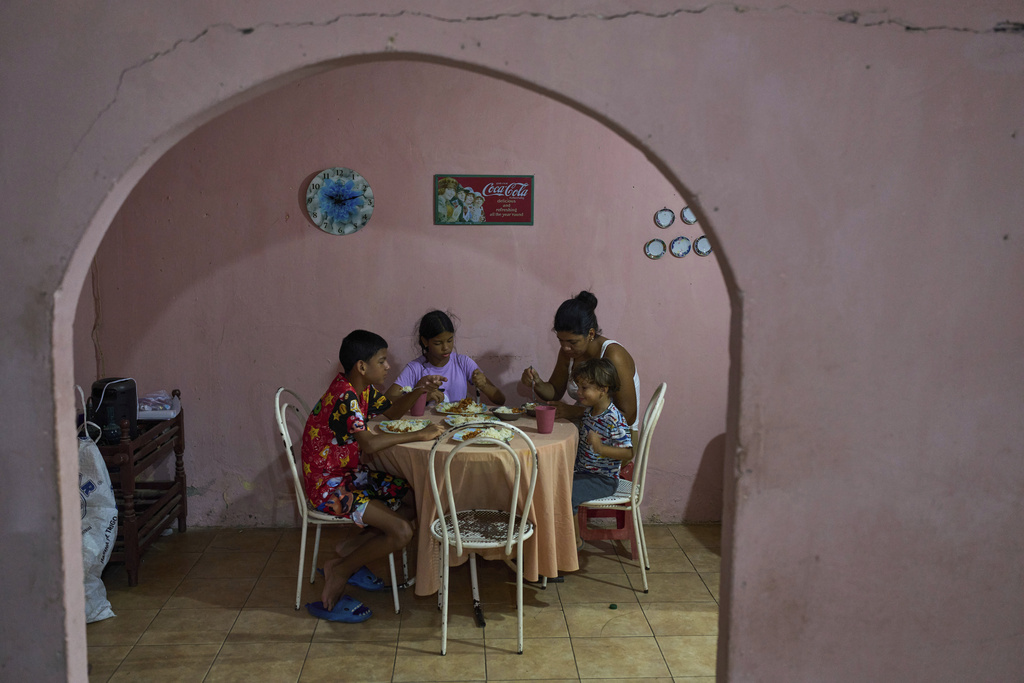 Three of Alnily Chirino's four children, and her grandson, eat dinner at home in Coro, Venezuela, Friday, June 27, 2025. (AP Photo/Ariana Cubillos)