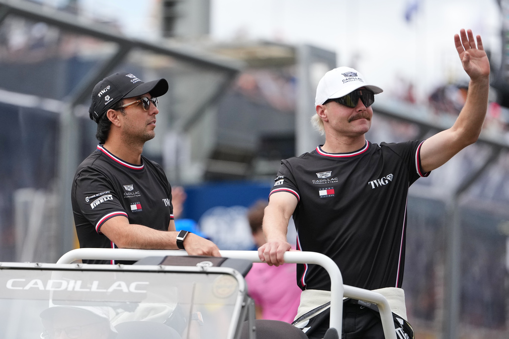 Cadillac driver Valtteri Bottas of Finland and teammate Sergio Perez of Mexico react during the drivers parade ahead of the Australian Formula One Grand Prix at Albert Park, in Melbourne, Australia, Sunday, March 8, 2026. (AP Photo/Asanka Brendon Ratnayake)