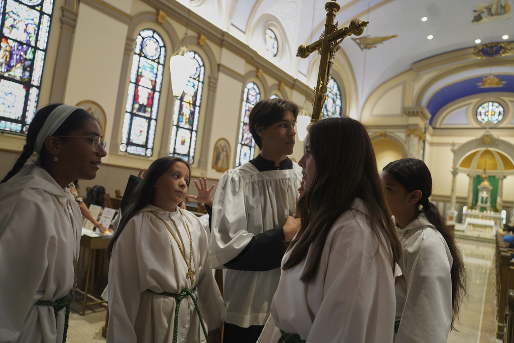 Altar boys and girls talk before service at Immaculate Conception Catholic Church on Sunday, Aug. 10, 2025, in Cedar Rapids, Iowa. (AP Photo/Jessie Wardarski)