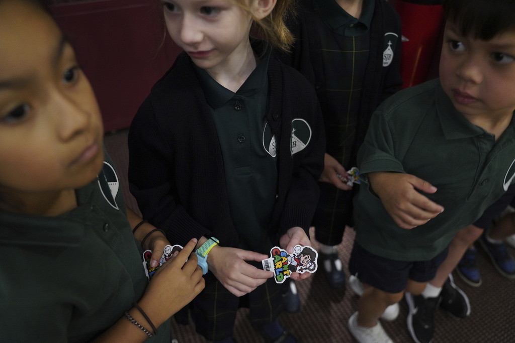 St. John Berchmans' school students hold stickers of Blessed Carlo Acutis, who will be canonized a saint by Pope Leo XIV, after Mass at Blessed Carlo Acutis Parish, on Wednesday, Sept. 3, 2025, in Chicago. (AP Photo/Jessie Wardarski)