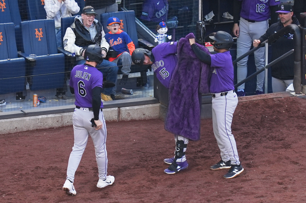 Colorado Rockies' Hunter Goodman (15), center, gets a fur coat after hitting a two-run home run during the third inning of the second baseball game of a doubleheader against the New York Mets, Sunday, April 26, 2026, in New York. (AP Photo/Seth Wenig)
