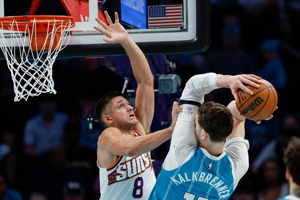 Charlotte Hornets center Ryan Kalkbrenner, right, drives to the basket against Phoenix Suns guard Grayson Allen (8) during the first half of an NBA basketball game in Charlotte, N.C., Thursday, April 2, 2026. (AP Photo/Nell Redmond)