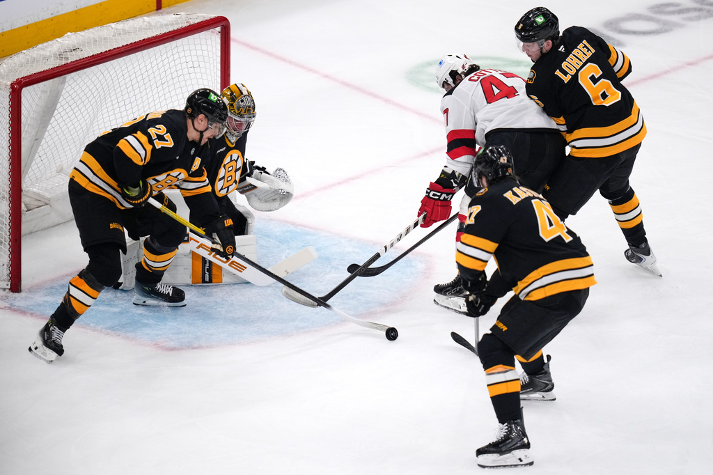 New Jersey Devils left wing Paul Cotter (47) is surrounded by Boston Bruins players while trying to shoot during the first period of a hockey game, Tuesday, April 14, 2026, in Boston. (AP Photo/Charles Krupa)