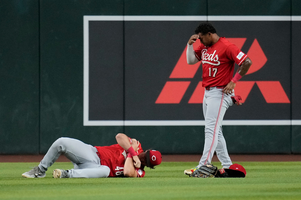 An injured Cincinnati Reds left fielder Michael Toglia (48) holds his shoulder as Reds center fielder Dane Myers (17) looks on during the first inning of a baseball game against the Arizona Diamondbacks, Friday, Aug. 21, 2026, in Phoenix. (AP Photo/Ross D. Franklin)