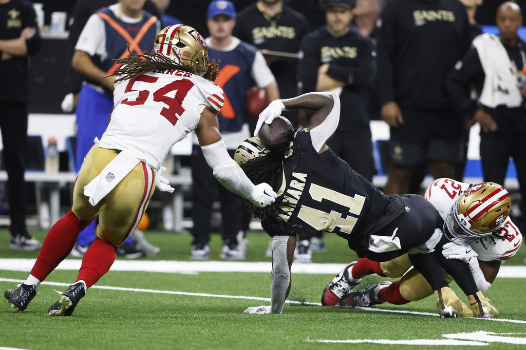 New Orleans Saints running back Alvin Kamara (41) is brought down by San Francisco 49ers safety Ji'Ayir Brown, right, before fumbling the ball, which was recovered by linebacker Fred Warner (54), during the second half of an NFL football game in New Orleans, Sunday, Sept. 14, 2025. (AP Photo/Butch Dill)