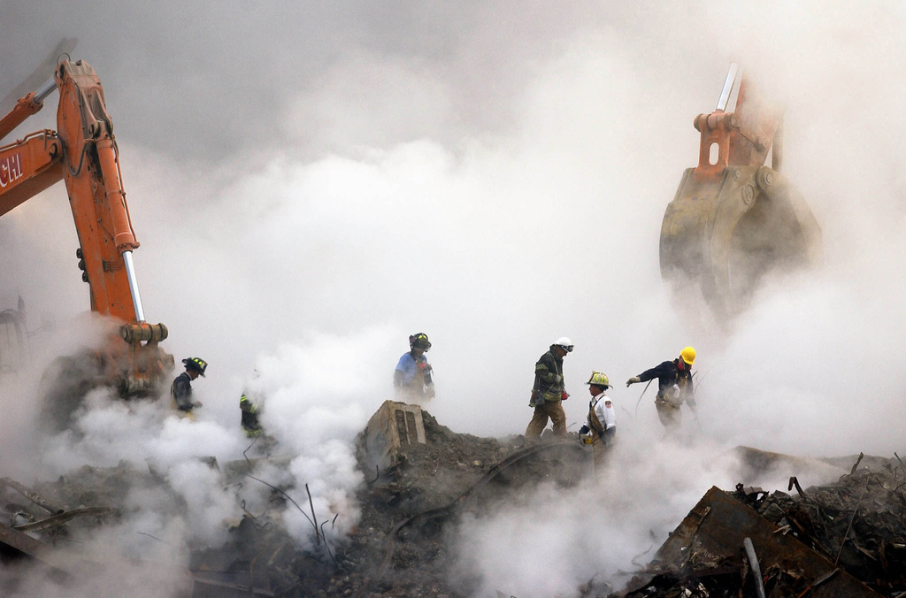 FILE - Firefighters walk over the ruins of the World Trade Center, through clouds of dust and smoke, at ground zero in New York on Oct. 11, 2001. (AP Photo/Stan Honda, Pool, File)