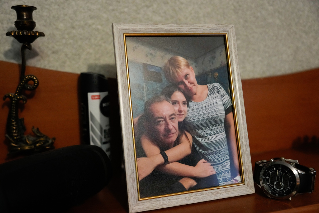A family photo of Dmytro with his daughter Ekaterina and wife Tetiana is displayed at the family's multi-generational home next to the watch that Dmytro was wearing when he was killed by a Russian strike last year on the Ukrainian thermal power plant where he worked, Wednesday, Oct. 29, 2025. (AP Photo/Julia Demaree Nikhinson)