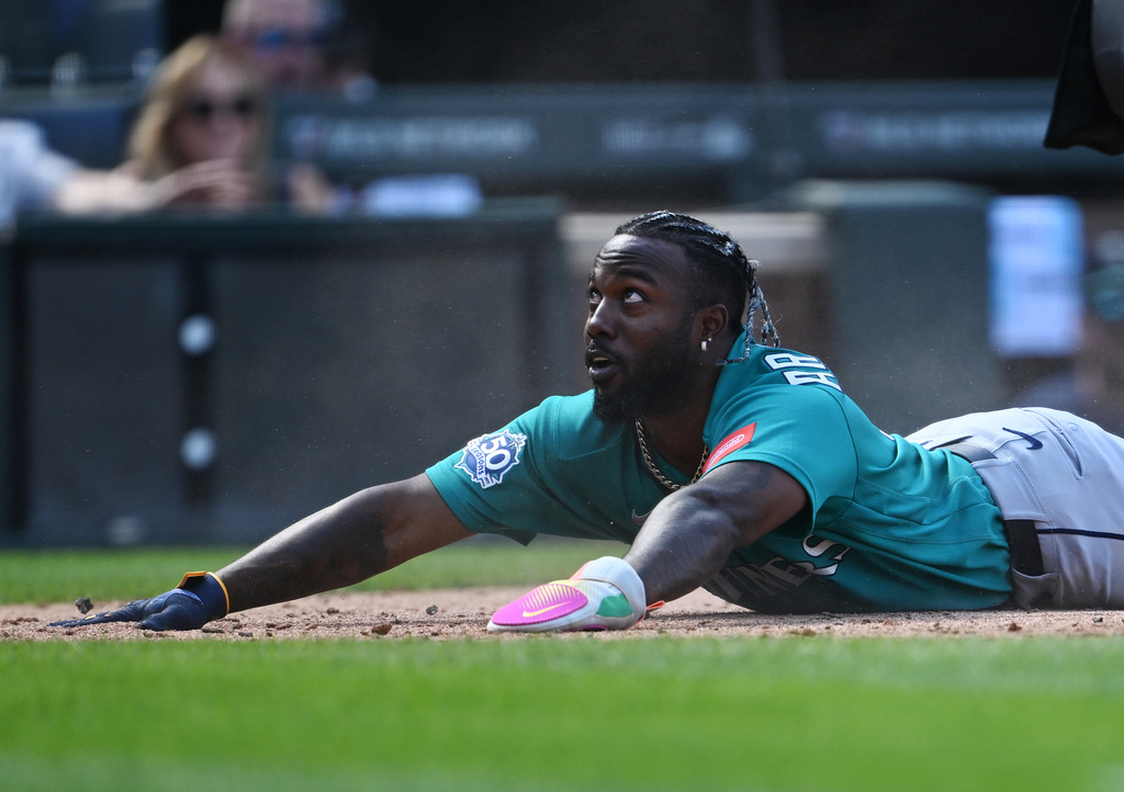 Seattle Mariners' Randy Arozarena looks up at a teammate after sliding safely into home in the fourth inning against the Colorado Rockies during a baseball game Sunday, Sept. 20, 2026, in Denver. (AP Photo/RJ Sangosti)