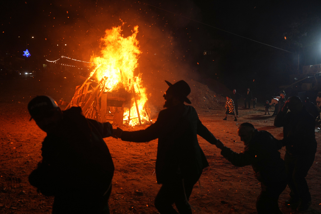 Ultra-Orthodox Jews dance around a bonfire during Lag BaOmer, a Jewish holiday traditionally marked by bonfire, music, and communal celebrations, in Netanya, Israel, Monday, May 4, 2026. (AP Photo/Ariel Schalit)