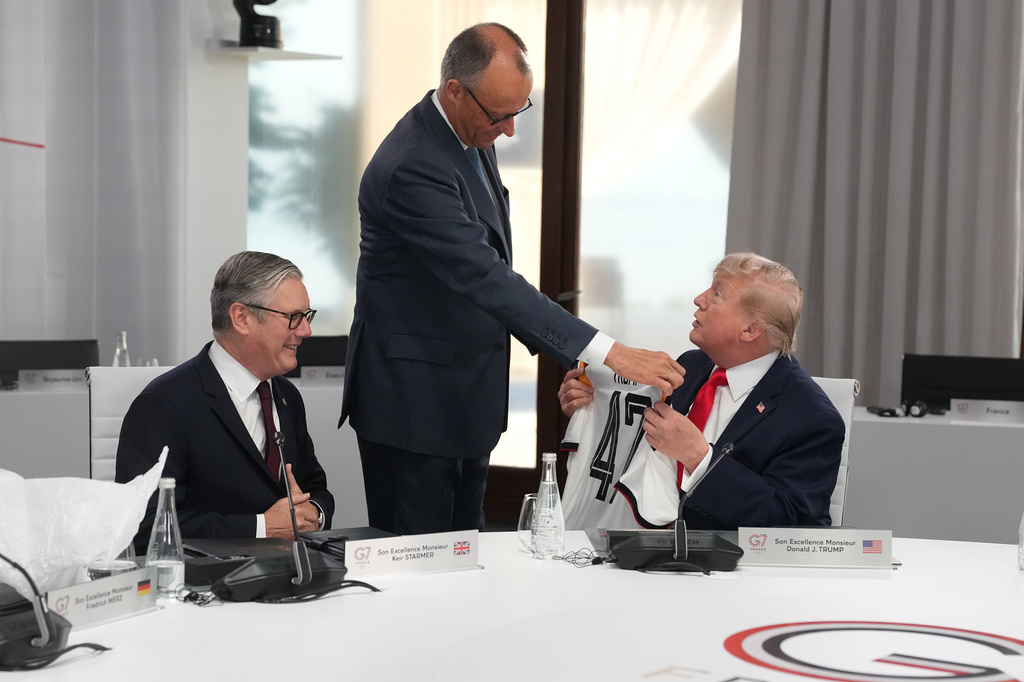 German Chancellor Friedrich Merz, center, presents U.S. President Donald Trump, right, with a jersey with the number 47 on it as British Prime Minister Keir Starmer, left, looks on during a working session at the G7 summit in Evian-les-Bains, France, Tuesday, June 16, 2026. (AP Photo/Thibault Camus, Pool)