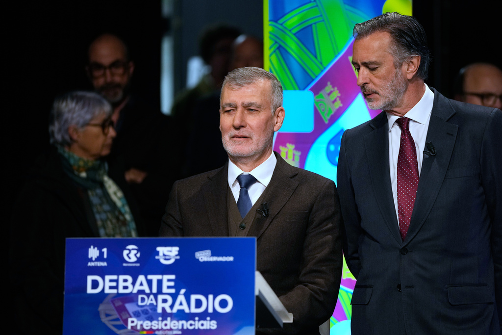 Candidate Joao Cotrim de Figueiredo of the Liberal Initiative party looks over the shoulder of Henrique Gouveia e Melo, a retired Rear Admiral running as an independent, as they wait for the start of a presidential election radio debate at a studio in Lisbon, Friday, Jan. 2, 2026. (AP Photo/Armando Franca)