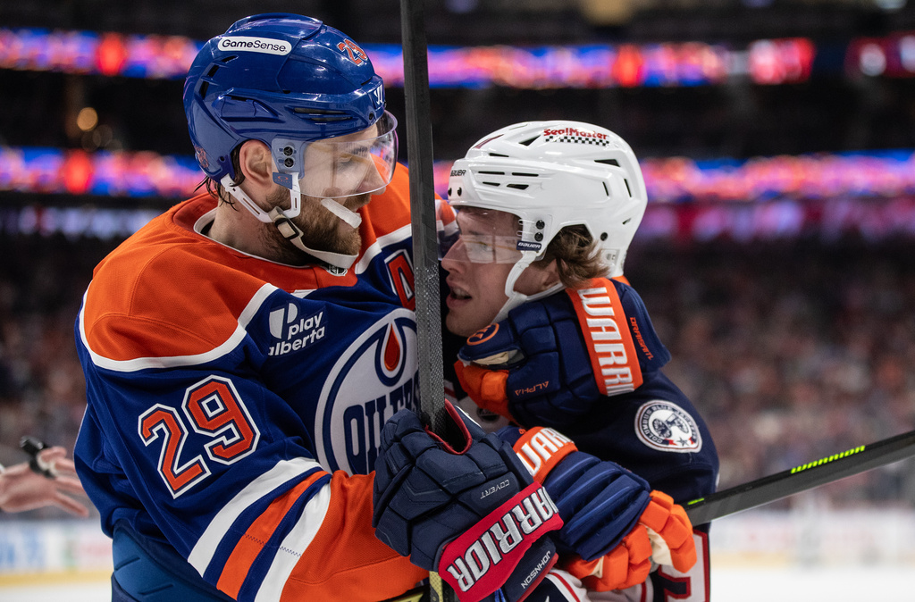 Columbus Blue Jackets' Kent Johnson, right, and Edmonton Oilers' Leon Draisaitl (29) rough it up during first-period NHL hockey game action in Edmonton, Alberta, Monday, Nov. 10, 2025. (Jason Franson/The Canadian Press via AP)