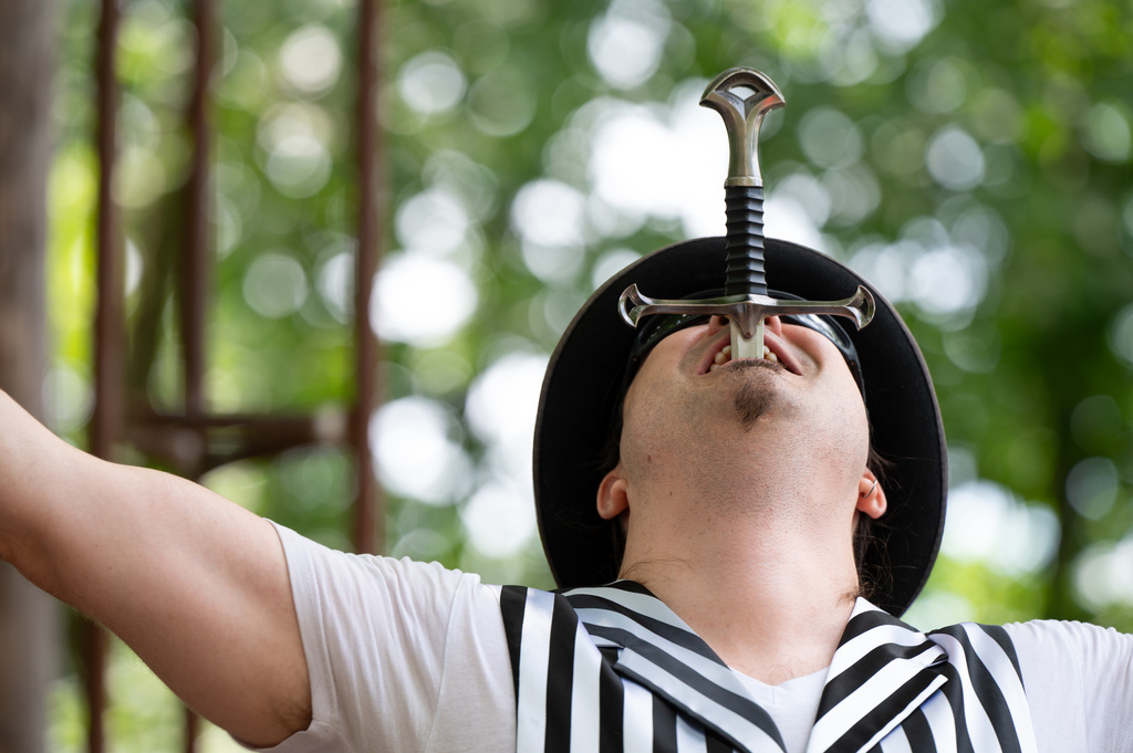 Nathan Wakefield, the new owner of Mystery Hill, swallows a sword during a pop-up carnival at the roadside attraction Onsted, Mich., on Saturday, July 18, 2026. (Ella Miller/Bridge Michigan via AP)