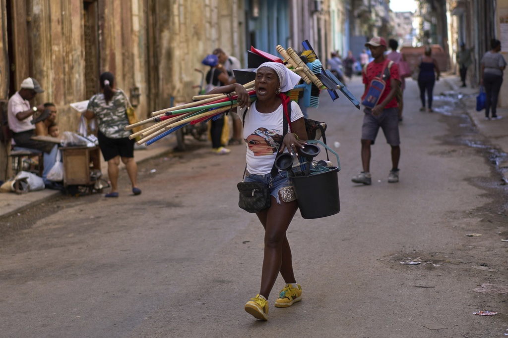 A vendor hawks brooms, dustpans, and toilet plungers in Havana, Aug. 28, 2025. (AP Photo/Ramón Espinosa)